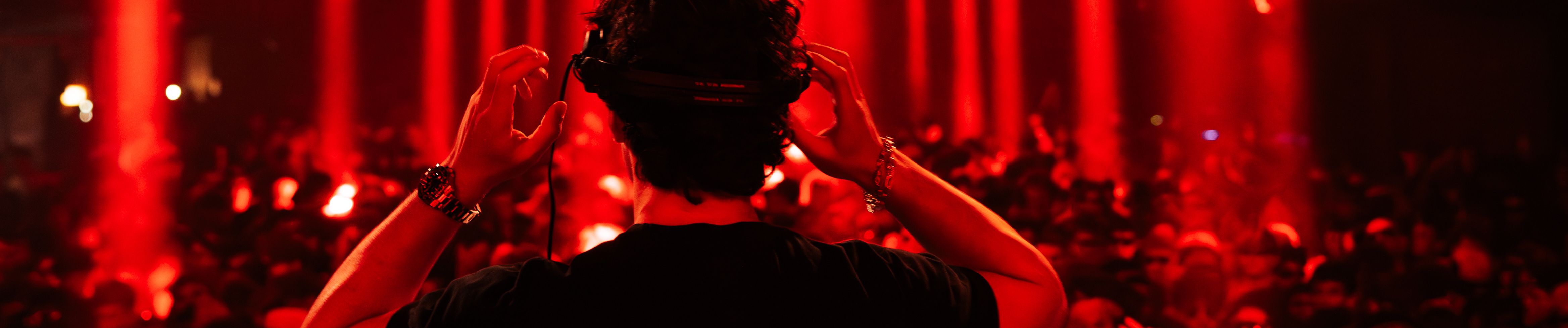 Gavin Blac at the DJ booth facing a red-lit crowd